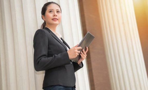 young smiling female holding mobile pad outside of government building